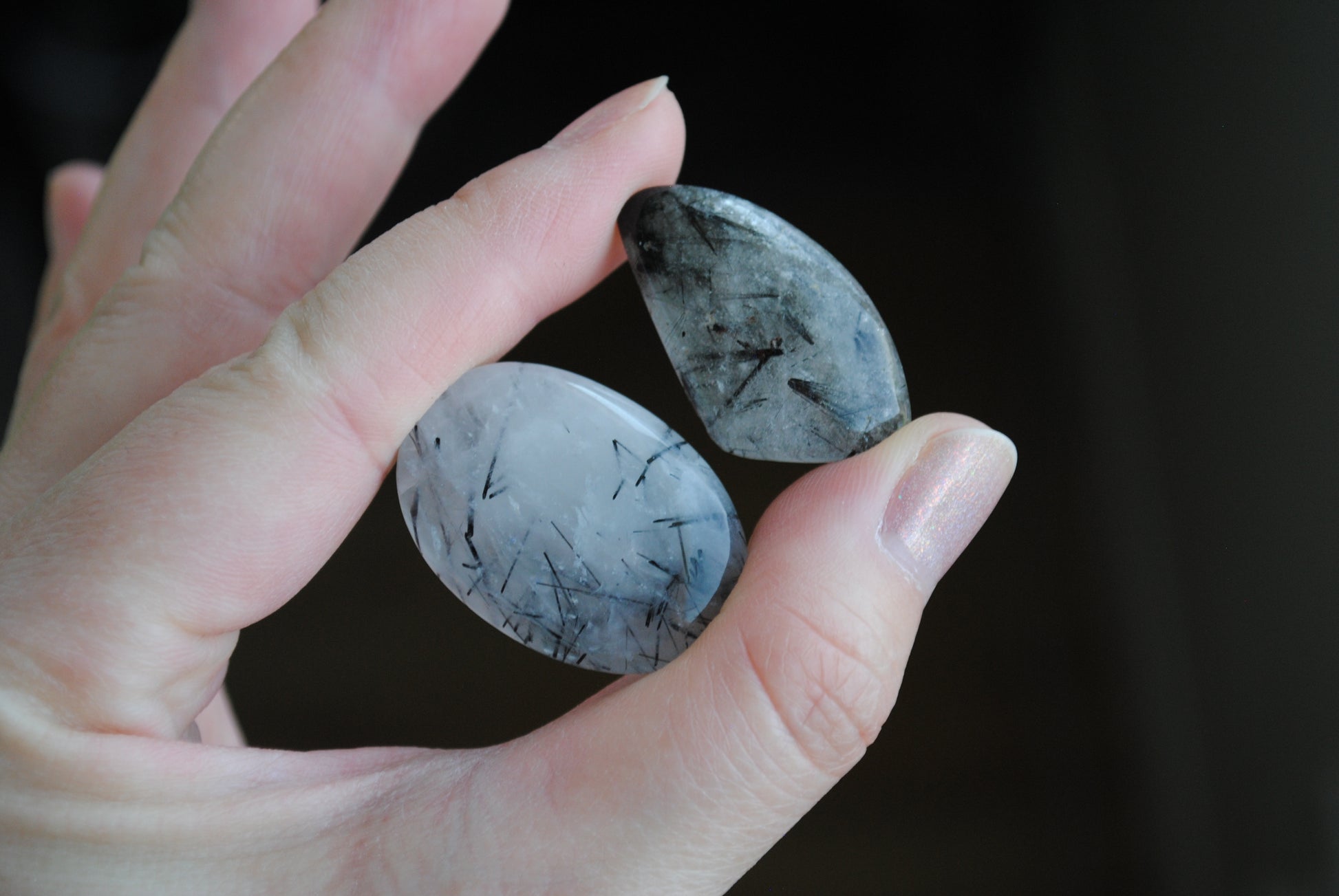 Tourmalinated quartz cabochons in fingers