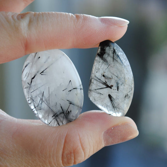 Tourmalinated quartz cabochons held in fingers 