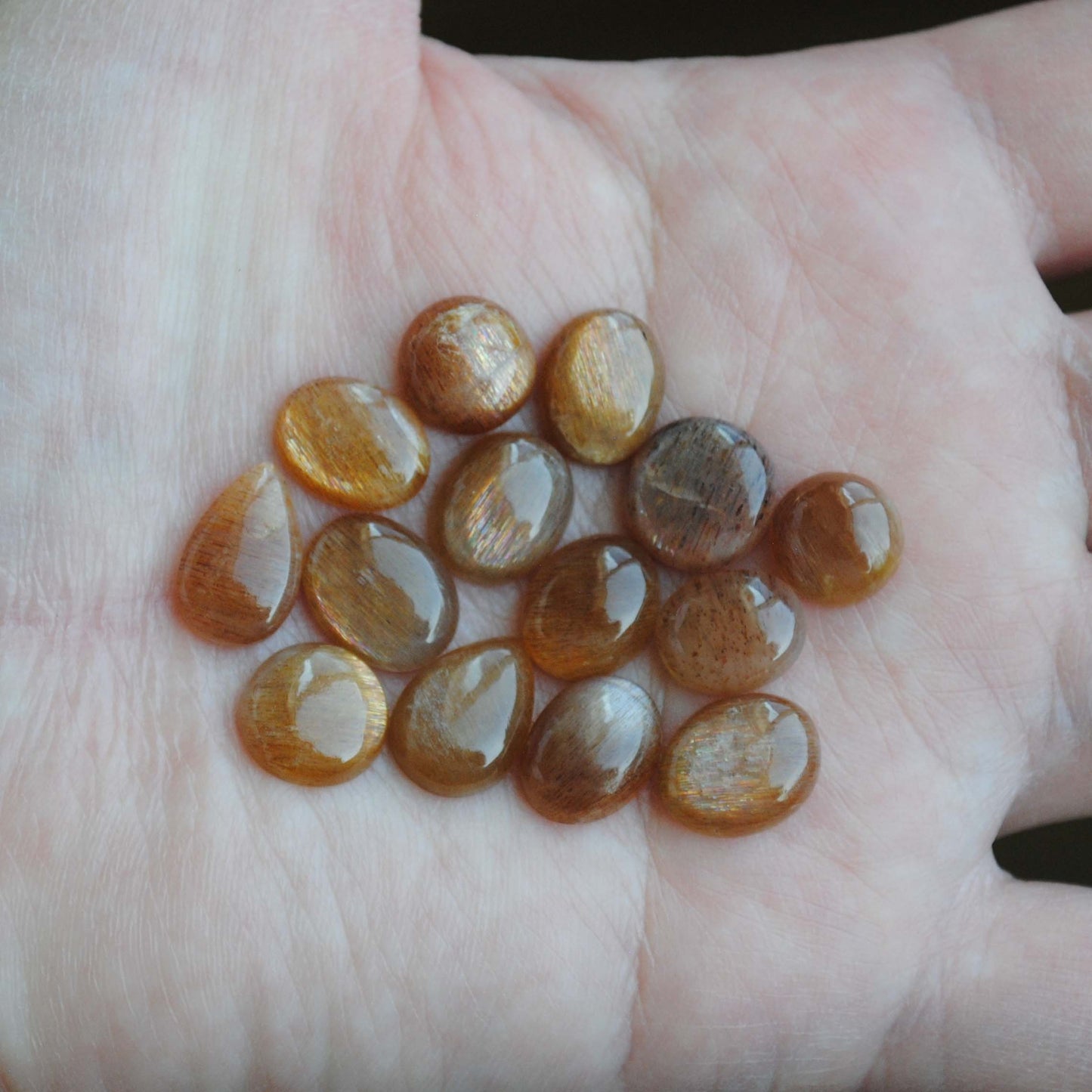 Golden sheen moonstone cabochons on palm of hand