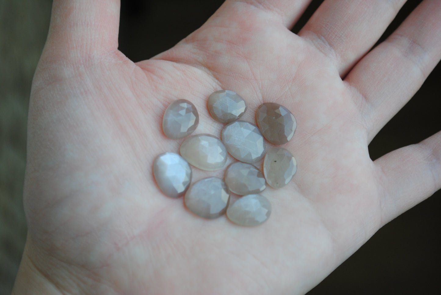 Grey moonstone rose cut cabochons on palm of hand