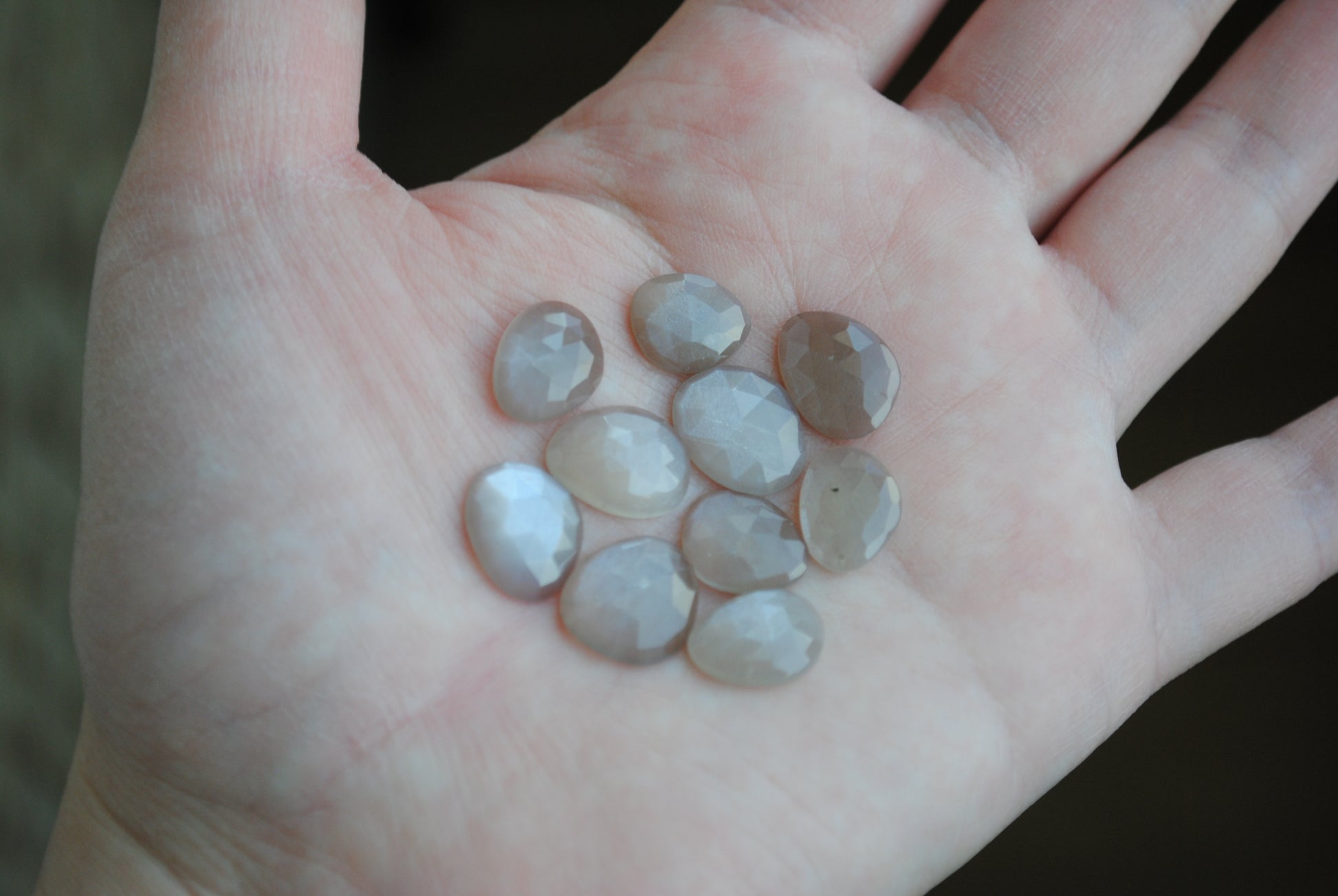 Grey moonstone rose cut cabochons on palm of hand