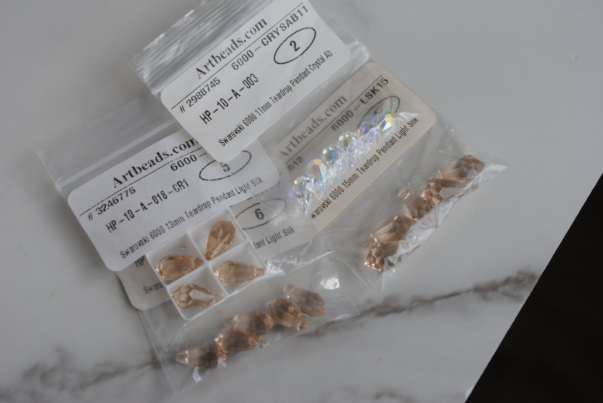 Swarovski teardrop in bags on light background